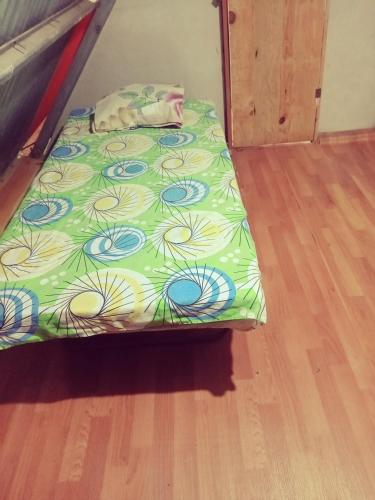 a bed with a green comforter on a wooden floor at Cabaña sinfonía natural in El Quije