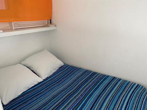 une petite chambre avec un lit à rayures bleues et blanches dans l'établissement Le Boisvinet de la plage, à Saint-Gilles-Croix-de-Vie