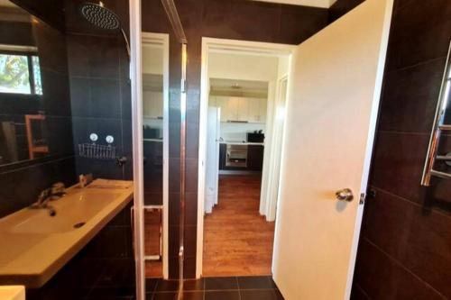 ein Bad mit einem Waschbecken und einem Spiegel in der Unterkunft Summer Breeze - Holiday Or Business Apartment in Perth