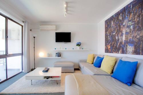 Chic 2 Bed Apartment On Scarborough Beach في بيرث: غرفة معيشة مع أريكة وتلفزيون
