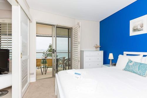 een slaapkamer met een blauwe accentmuur en een bed bij The White Pearl Penthouse in Perth