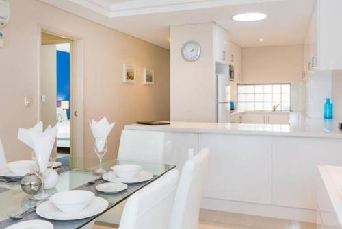 kuchnia ze szklanym stołem i białymi urządzeniami w obiekcie The White Pearl Penthouse w mieście Perth