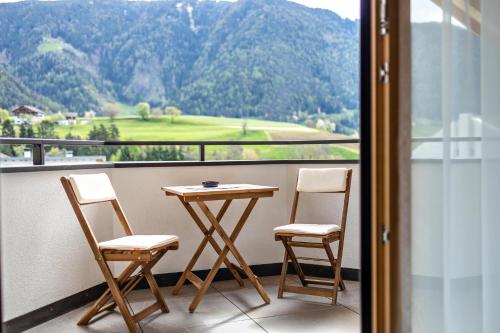 a table and two chairs on a balcony with a view at Krämerhof Apt Aferer Geisler in Rodengo