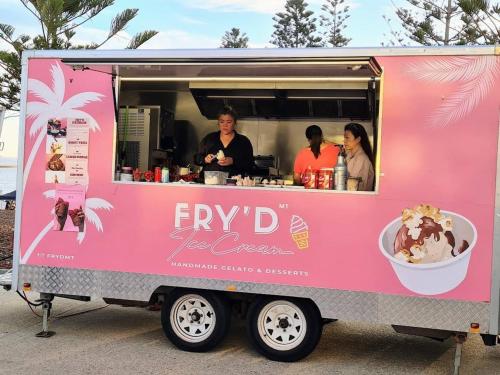 a pink food truck with three people ordering food at Sunset On Esplanade in Perth
