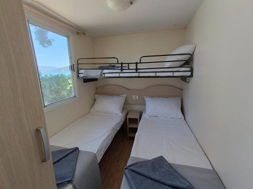 2 Etagenbetten in einem kleinen Zimmer mit Fenster in der Unterkunft Camping Karavomilos in Sami