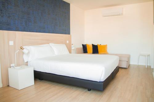 a bedroom with a large white bed and a couch at Select Porto Suites in Porto
