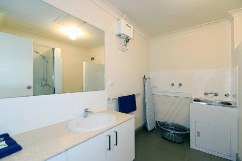 a white bathroom with a sink and a shower at West Beach Lagoon 216 - Quiet & Relaxing in Perth