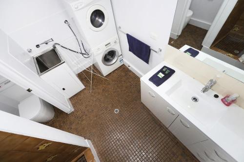 uma casa de banho com um lavatório e uma máquina de lavar roupa em West Beach Lagoon 221 - Stylish Apartment! em Perth
