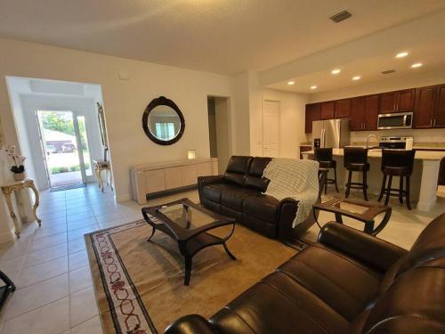 a living room with a leather couch and a kitchen at Home sweet home in Port Saint Lucie