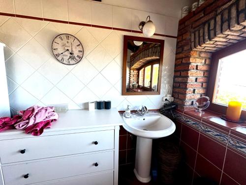 a bathroom with a sink and a clock on the wall at The Shire in Poljane