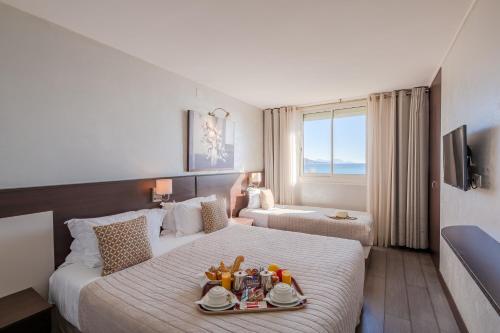 Una habitación de hotel con una cama con una bandeja de comida. en Hôtel La Plage, en Sainte-Maxime