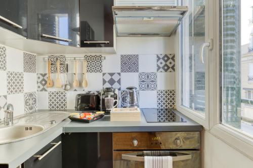 eine kleine Küche mit einem Waschbecken und einem Fenster in der Unterkunft Escale à Nairobi-Portes de Paris-PARKING in Saint-Ouen