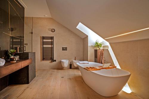 baño con bañera blanca grande y lavamanos en Hotel Cigarral Santa María, en Toledo