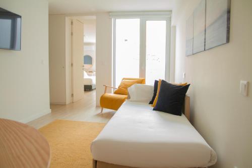 Pokój z łóżkiem i pomarańczowym krzesłem w obiekcie room Select Porto Suites w Porto