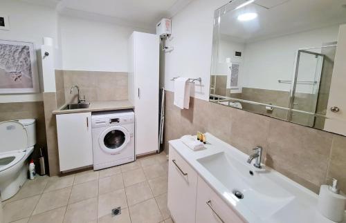 a bathroom with a sink and a washing machine at Beach Break Iconic Scarborough in Perth
