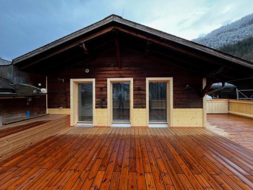 een huis met een houten terras met bergen op de achtergrond bij Penthouse at The Bären 180º View in Zweisimmen