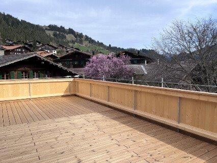 a large patio with a fence and a purple tree at Region de Gstaad - Ultra Modern Apartment- Huge Roof Terrace - Great Views in Zweisimmen
