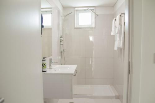 a white bathroom with a shower and a sink at room Select Porto Suites in Porto