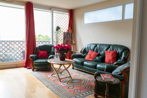 un salon avec un canapé en cuir noir et une table dans l'établissement Charming duplex with two balconies in the 13th, à Paris