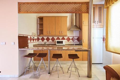 una cocina con encimera con taburetes. en Apartamentos San Andres, en Sevilla