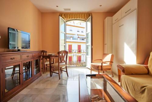 sala de estar con TV, mesa y sillas en Apartamentos San Andres, en Sevilla