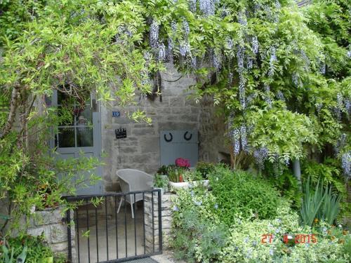 einen Garten mit einem Tor und ein Haus mit Blumen in der Unterkunft La Pie qui Chante in Saint-Lamain