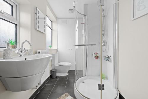 a white bathroom with a tub and a toilet at Fantastic, modern 3 bedroom house in Manchester