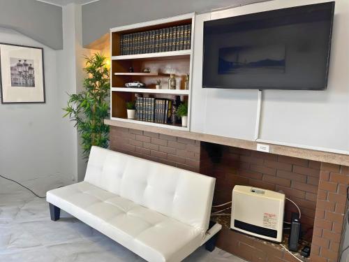 a white bench in a living room with a tv at Sea View Court Kobe in Kobe