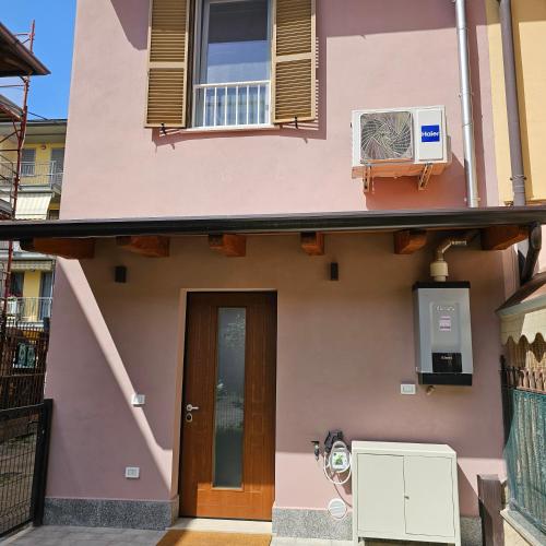 a pink house with a door and a air conditioner at Casetta Meravigliosa Paullo in Paullo