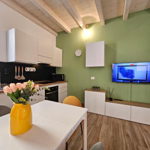a kitchen with white cabinets and a vase of flowers on a table at Casetta Meravigliosa Paullo in Paullo
