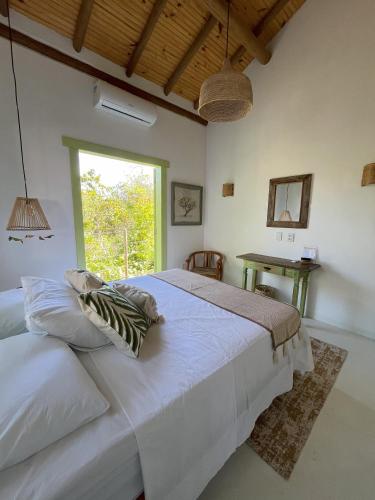 a bedroom with a large white bed and a window at Morada Pochixá in Corumbau