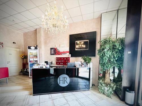 a lobby with a reception desk and a chandelier at Hotel Romagna in Cesena