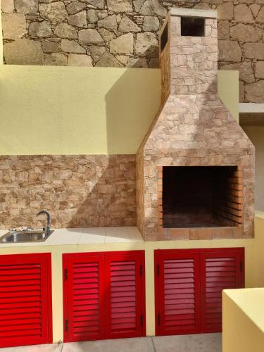 a kitchen with red cabinets and a stone fireplace at Angela Beach Place in Vila Baleira