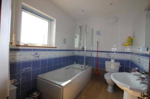 a bathroom with a tub and a toilet and a sink at Spacious seaside family house in Aberdaron with large garden and stunning sea views in Aberdaron