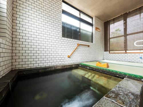 a large pool of water in a bathroom with a tub at Yufuin Wasaku in Yufu