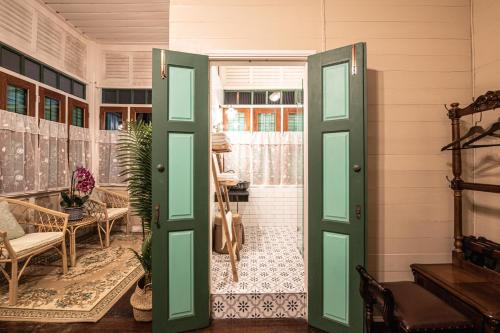 een kamer met groene deuren en een kamer met een tafel bij Wallaya Heritage Stay in Bangkok