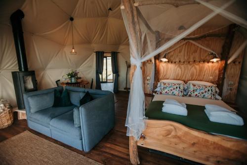 a bedroom with a bed and a couch in a tent at Dome Meadow 1 with Log Burning Tub At Tapnell Farm in Yarmouth