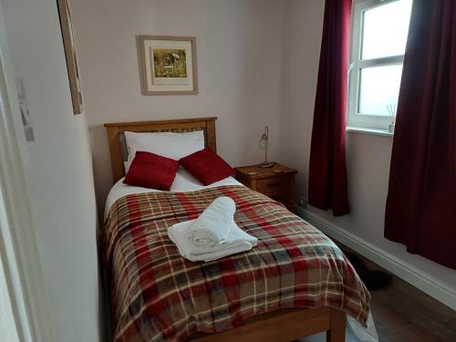 a bedroom with a bed with two red pillows at Central Ripon - Sleeps 3 - Garden - Pet Friendly in Ripon