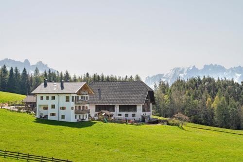 a large white house on a hill with a green field at Ebnerhof in Collalbo