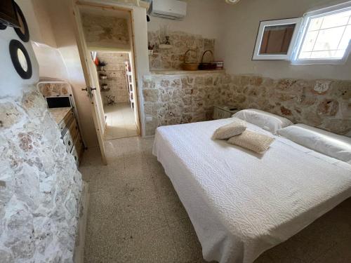 ein Schlafzimmer mit einem Bett in einem Zimmer mit Steinwänden in der Unterkunft Trullo Del Salento in San Vito dei Normanni