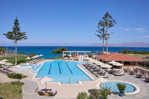 eine Aussicht über den Pool des Resorts mit Stühlen und Sonnenschirmen in der Unterkunft Ammos Luxury Resort in Mastichari