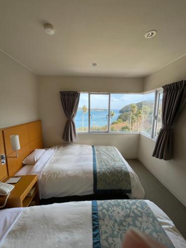 um quarto de hotel com duas camas e uma grande janela em Wisterian Life Club Toba em Toba