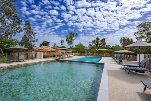 a swimming pool with lounge chairs and umbrellas at Camping l'Oso in Porto-Vecchio