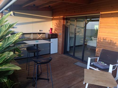 eine kleine Küche mit einem Tisch und Stühlen auf einer Terrasse in der Unterkunft Bungalow de luxe en bois avec Spa in La Possession