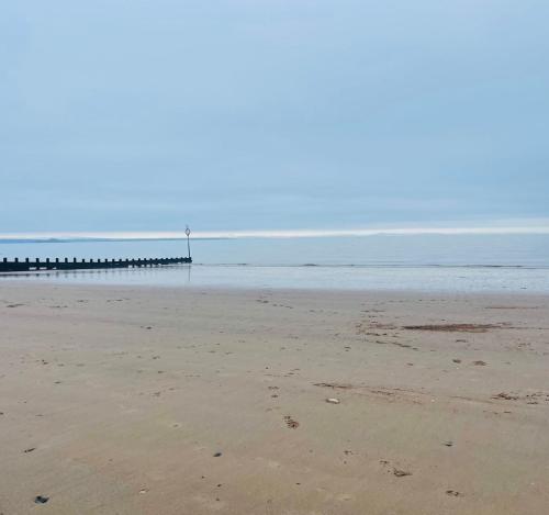 an empty beach with a pier in the distance at Cabin by the coast in Edinburgh