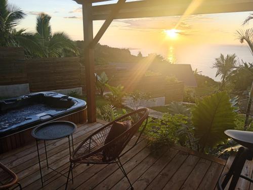 a hot tub sitting on a deck with the sunset at Bungalow de luxe en bois avec Spa in La Possession