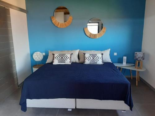 Dormitorio azul con cama y pared azul en Bungalow de luxe en bois avec Spa en La Possession