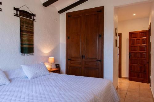 een slaapkamer met een wit bed en een houten deur bij La Paz in El Tosalet
