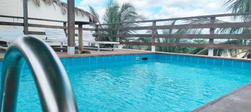 a blue swimming pool with a fence and a bench at Pousada Tropical Brasil Jeri in Jericoacoara