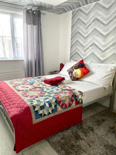 un letto con una trapunta in una camera da letto di Westfield Gardens Apartment - 3 bedrooms a Goodmayes